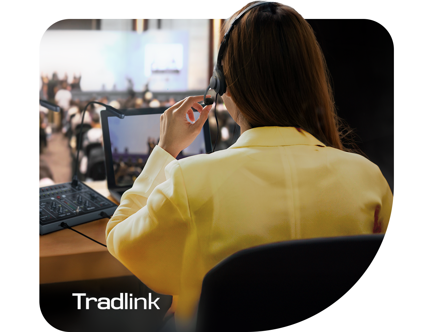 Mulher de costas em cabine acústica realiza tradução simultânea com headset e central de intérpretes Tradlink, da Riole.
